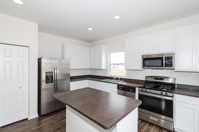 kitchen with a kitchen island, appliances with stainless steel finishes, white cabinetry, sink, and dark wood-type flooring