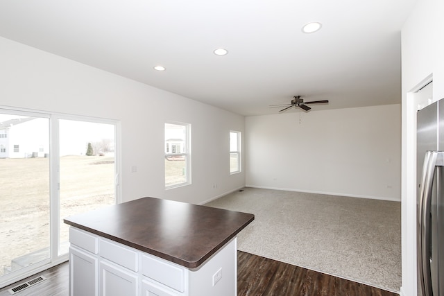 kitchen featuring stainless steel fridge, ceiling fan, white cabinets, a kitchen island, and dark hardwood / wood-style flooring