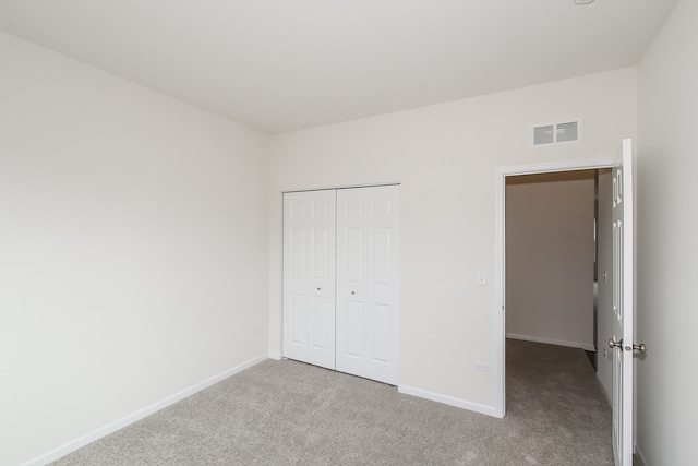 unfurnished bedroom featuring light colored carpet and a closet