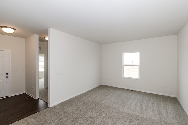 unfurnished room with dark colored carpet and plenty of natural light