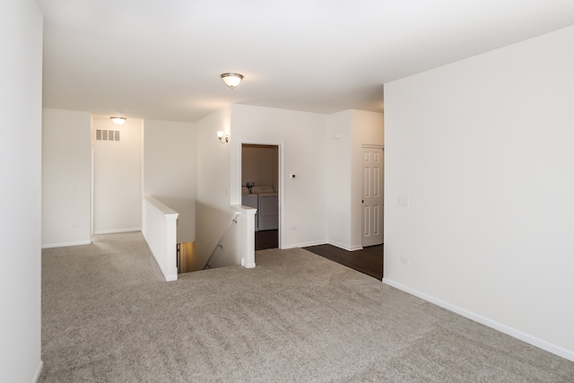 spare room with independent washer and dryer and dark carpet