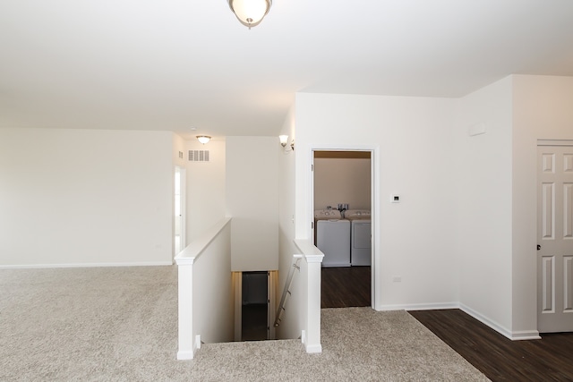 hall featuring separate washer and dryer and dark colored carpet