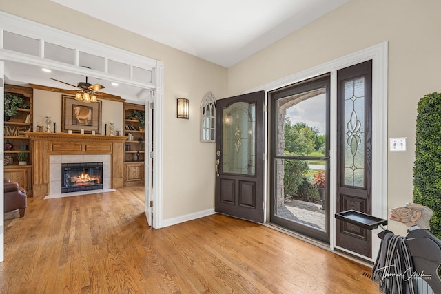 entryway with a tiled fireplace, hardwood / wood-style flooring, and ceiling fan