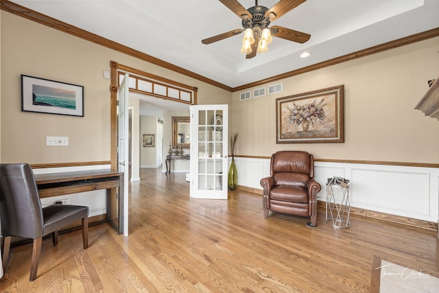 sitting room featuring ornamental molding, ceiling fan, a raised ceiling, light wood-type flooring, and french doors