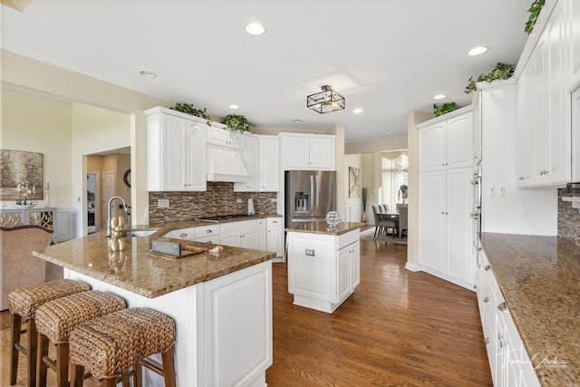 kitchen with a kitchen island, appliances with stainless steel finishes, sink, and dark stone counters