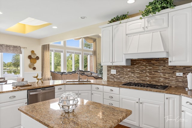 kitchen with stainless steel appliances, sink, white cabinets, and light stone counters