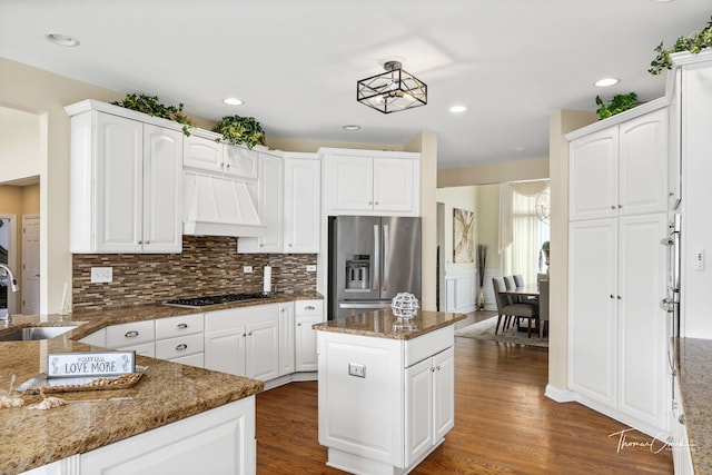 kitchen with premium range hood, a kitchen island, white cabinetry, dark stone counters, and stainless steel appliances