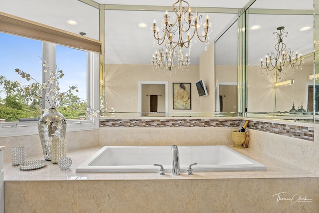 bathroom with tiled bath and a chandelier