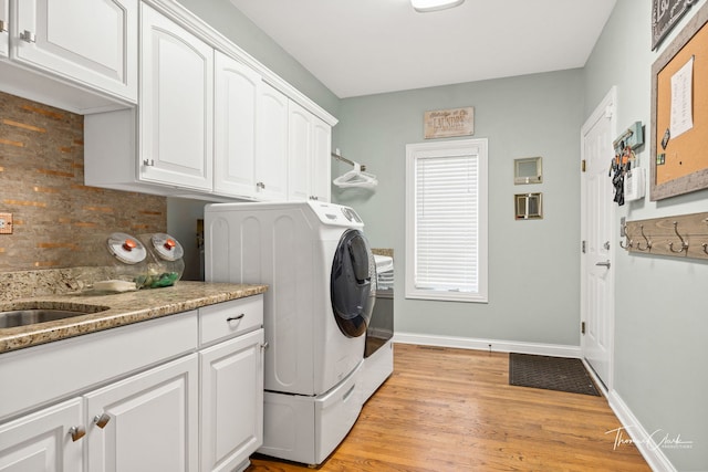 washroom with sink, light hardwood / wood-style flooring, washing machine and dryer, and cabinets