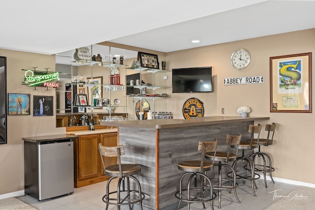 bar with light tile patterned floors and stainless steel refrigerator