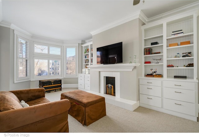 carpeted living room featuring a tiled fireplace, crown molding, and built in shelves