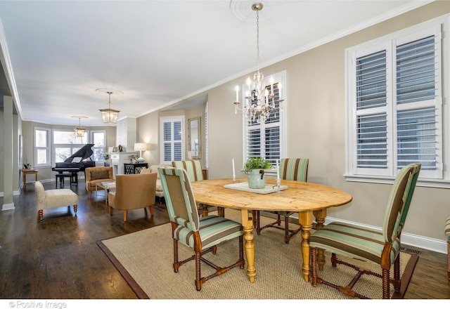 dining space with dark wood-type flooring, crown molding, and a chandelier