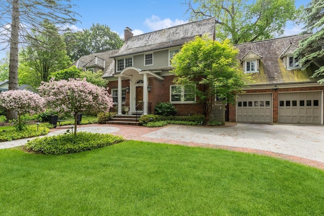 621 E Prospect Ave, Lake Bluff, IL 60044 - view of front of home with brick siding, a chimney, a front yard, a garage, and driveway