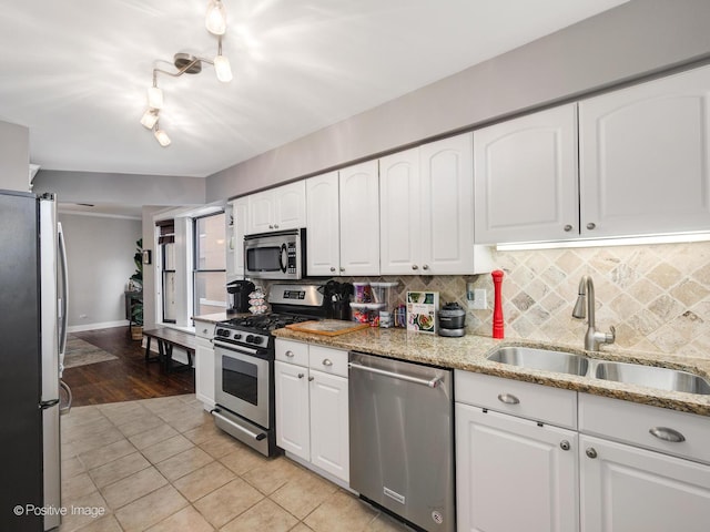 kitchen with sink, backsplash, stainless steel appliances, light stone countertops, and white cabinets