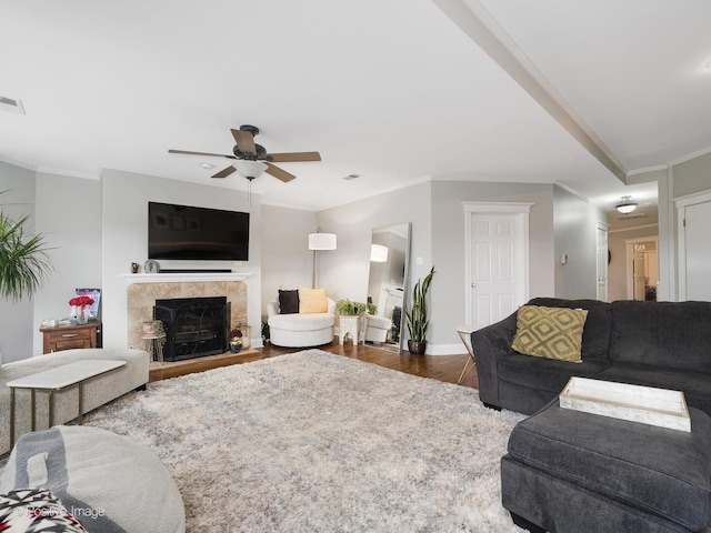 living room featuring crown molding, dark wood-type flooring, a tile fireplace, and ceiling fan