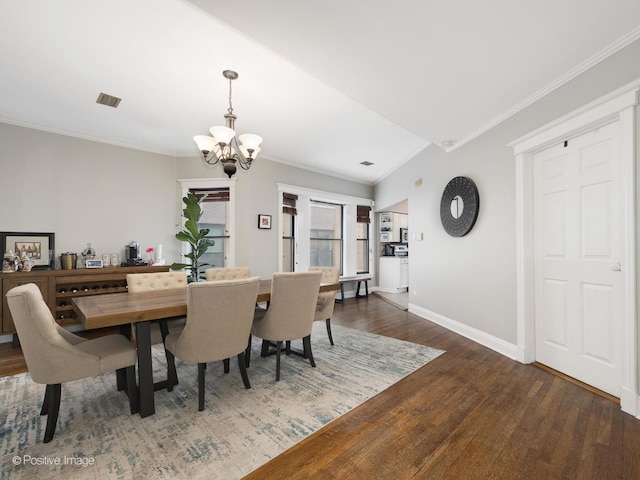 dining space featuring dark wood-type flooring, ornamental molding, and a chandelier