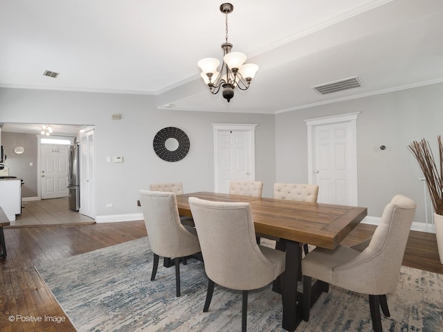 dining area with an inviting chandelier, ornamental molding, and dark hardwood / wood-style floors