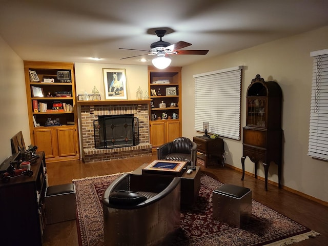 living room featuring dark wood-type flooring, ceiling fan, built in shelves, and a brick fireplace