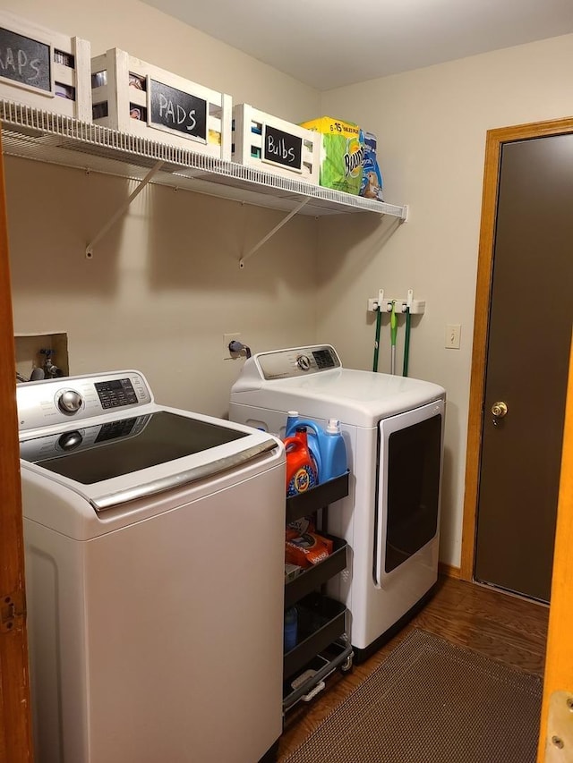 washroom with dark wood-type flooring and washer and clothes dryer