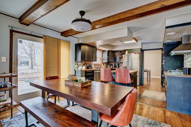 dining space featuring beam ceiling and light hardwood / wood-style flooring