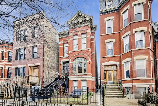 view of property with mansard roof, brick siding, and a fenced front yard