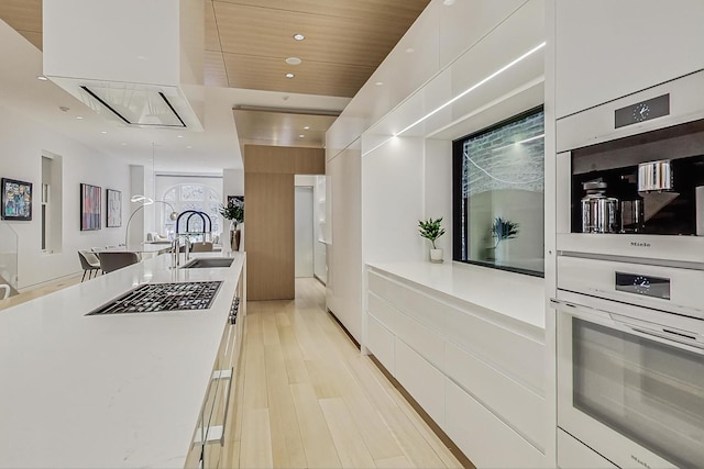 kitchen with white cabinetry, modern cabinets, light countertops, and a sink