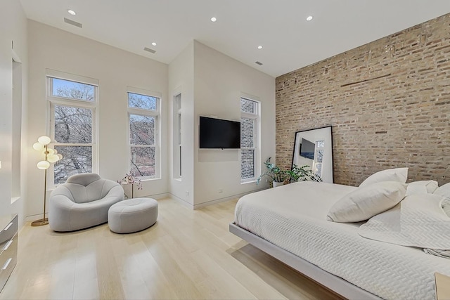 bedroom featuring visible vents, baseboards, brick wall, recessed lighting, and light wood-style floors