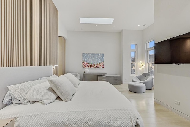 bedroom featuring access to exterior, baseboards, light wood-type flooring, recessed lighting, and a skylight