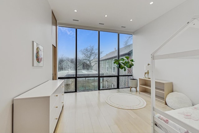 interior space with recessed lighting, a wall of windows, and wood finished floors