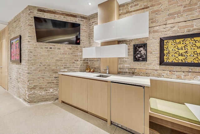 kitchen with wainscoting, brick wall, light countertops, and a sink