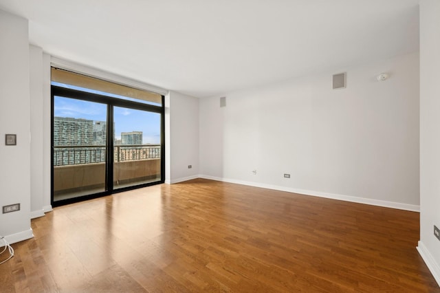 unfurnished room with wood-type flooring and a wall of windows