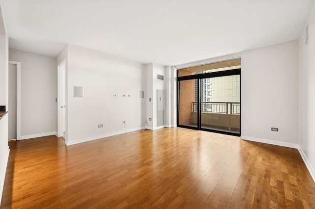 spare room with a wall of windows and light hardwood / wood-style floors