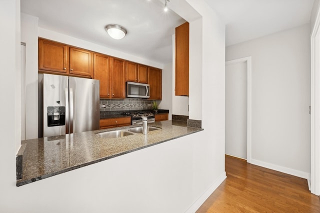 kitchen featuring dark stone countertops, sink, stainless steel appliances, and kitchen peninsula