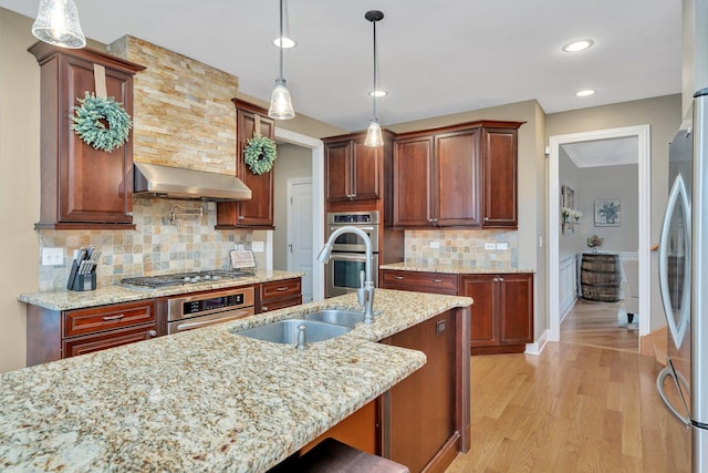 kitchen featuring ventilation hood, pendant lighting, a breakfast bar area, and appliances with stainless steel finishes