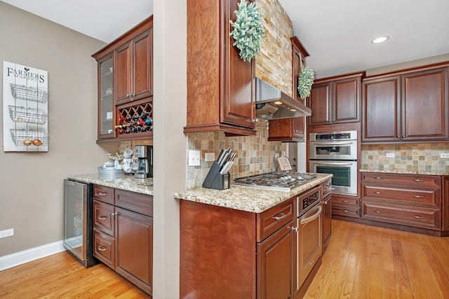 kitchen with wall chimney exhaust hood, appliances with stainless steel finishes, light hardwood / wood-style flooring, and wine cooler