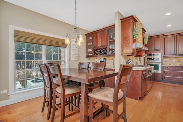 dining space with plenty of natural light, sink, a chandelier, and light hardwood / wood-style flooring