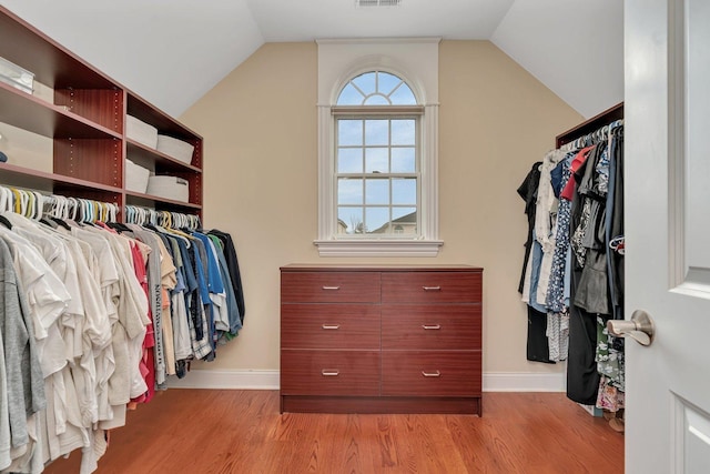 walk in closet with vaulted ceiling and light hardwood / wood-style floors