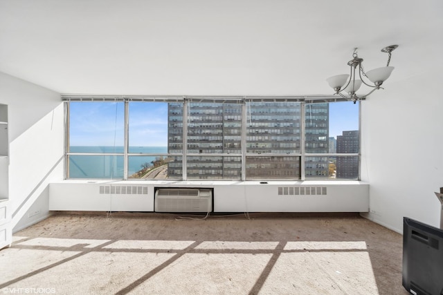 unfurnished sunroom with a healthy amount of sunlight, a wall mounted air conditioner, a chandelier, and a water view