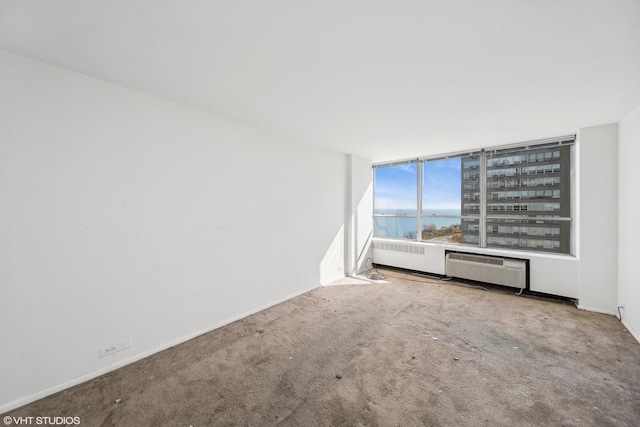 unfurnished room featuring a wall unit AC, light colored carpet, and a water view