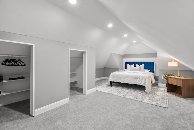 carpeted bedroom featuring lofted ceiling and a walk in closet