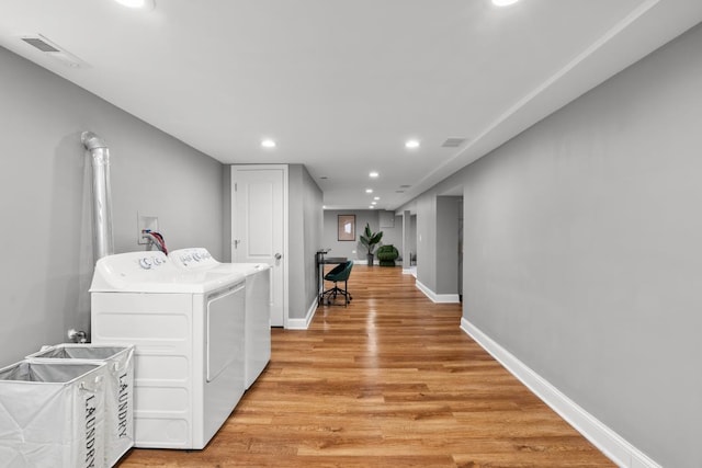 washroom with washing machine and dryer and light hardwood / wood-style flooring