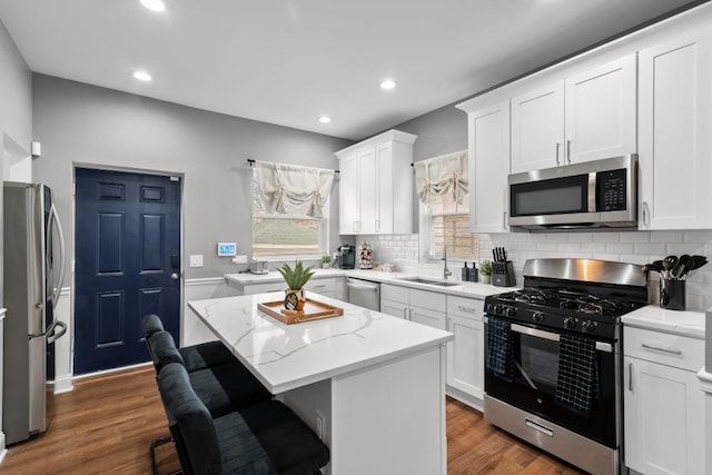 kitchen featuring appliances with stainless steel finishes, white cabinetry, sink, a kitchen breakfast bar, and a center island