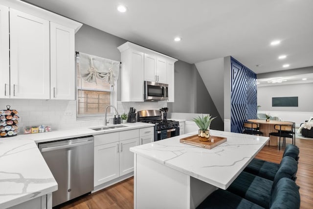 kitchen featuring sink, a breakfast bar area, white cabinetry, appliances with stainless steel finishes, and hardwood / wood-style floors