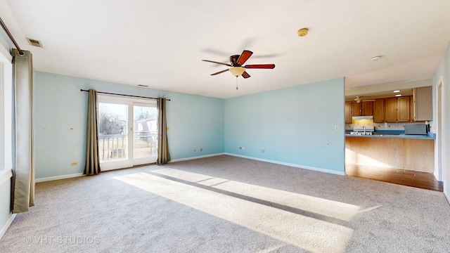 unfurnished living room featuring light carpet, ceiling fan, visible vents, and baseboards