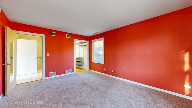 carpeted spare room featuring visible vents and baseboards