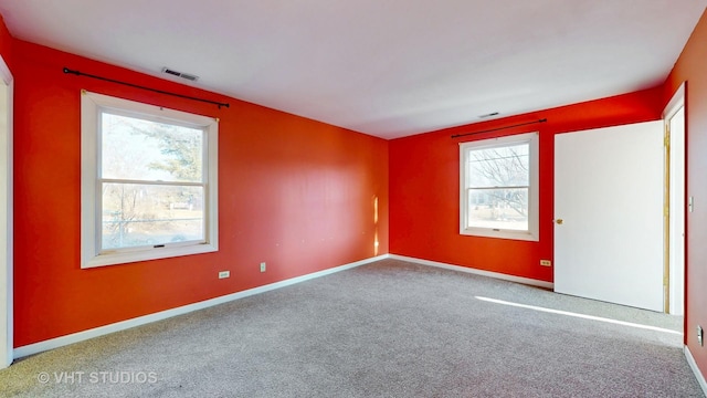 unfurnished room featuring carpet flooring, visible vents, and baseboards