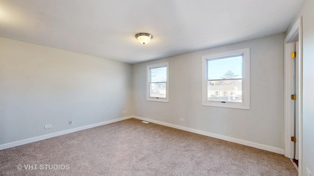 spare room with carpet floors, visible vents, and baseboards