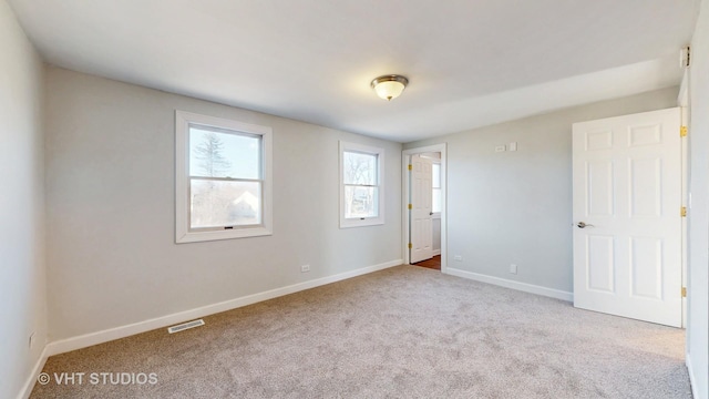 carpeted empty room with visible vents and baseboards