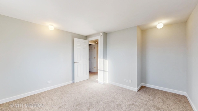 empty room featuring light colored carpet and baseboards