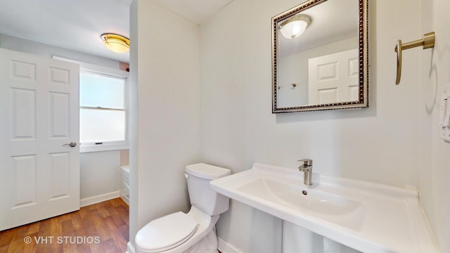 bathroom featuring toilet, baseboards, and wood finished floors